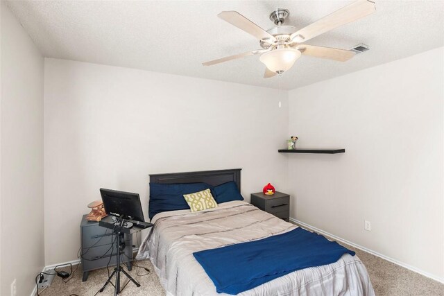 carpeted bedroom featuring ceiling fan and a textured ceiling