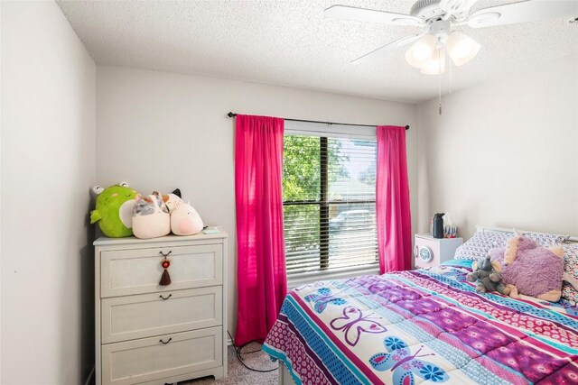 carpeted bedroom with ceiling fan and a textured ceiling