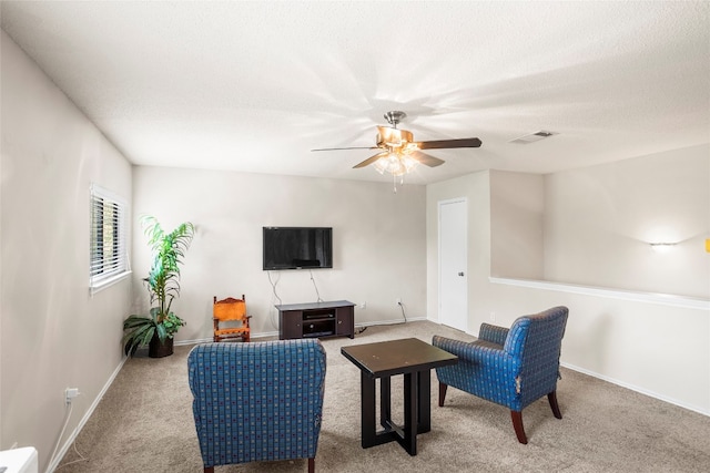 sitting room featuring ceiling fan, a textured ceiling, and light carpet