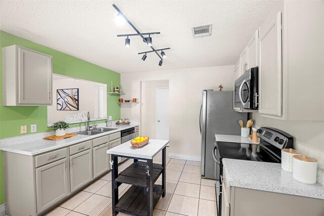 kitchen with track lighting, a textured ceiling, appliances with stainless steel finishes, and sink