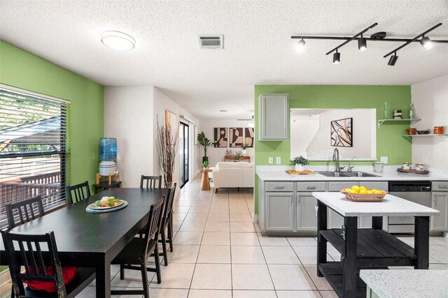 interior space with a textured ceiling, light tile patterned flooring, sink, and track lighting