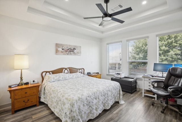 bedroom with a tray ceiling, dark wood-type flooring, and ceiling fan