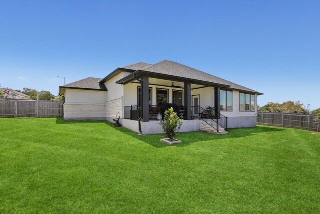 rear view of house featuring a lawn and ceiling fan