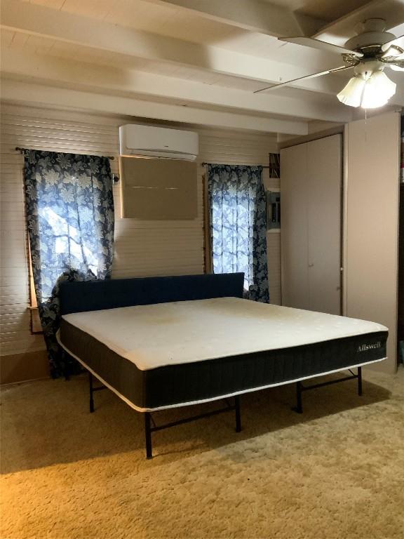 bedroom with ceiling fan, beamed ceiling, carpet, and a wall unit AC