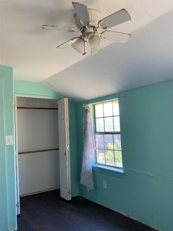 unfurnished bedroom with ceiling fan, lofted ceiling, and a closet