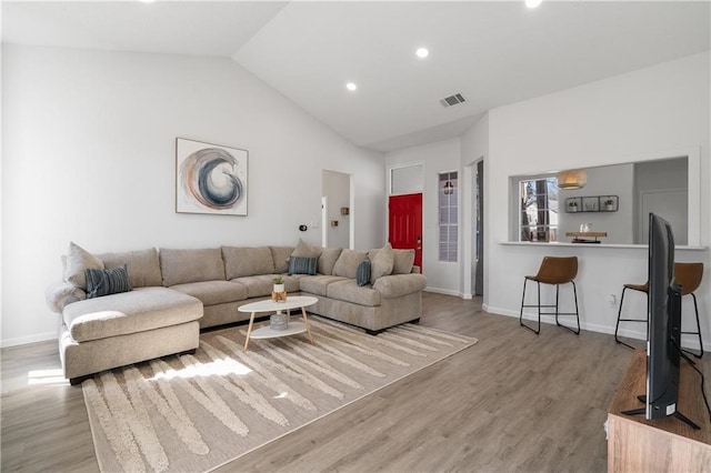 living room featuring light wood-type flooring and vaulted ceiling