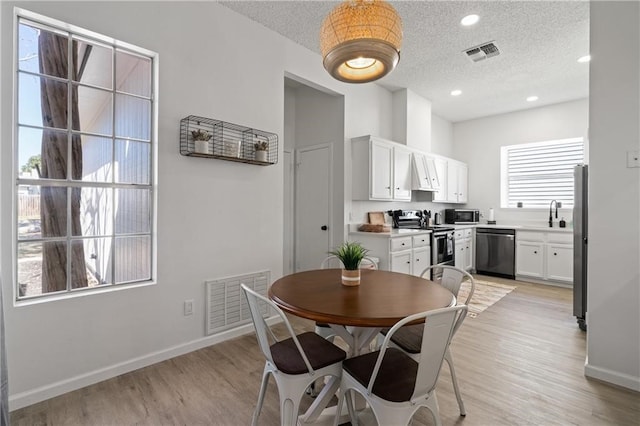 dining space with a textured ceiling, sink, and light hardwood / wood-style floors