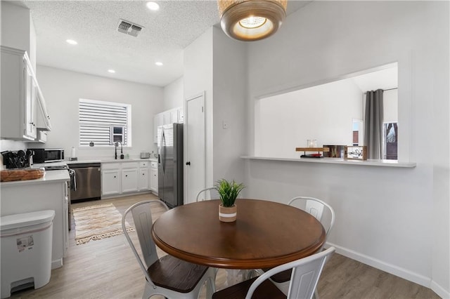 dining area with a textured ceiling and light hardwood / wood-style floors