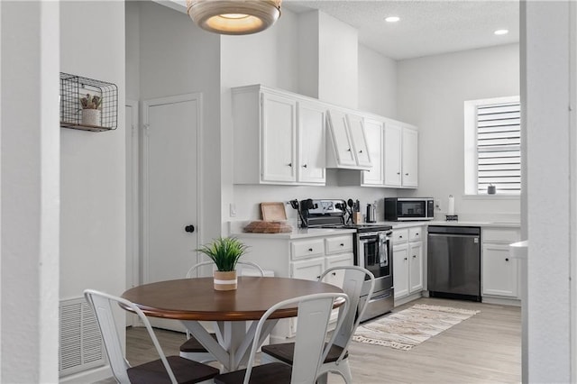 kitchen featuring a textured ceiling, light hardwood / wood-style flooring, stainless steel appliances, and white cabinets