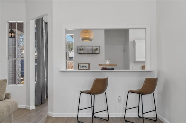 kitchen featuring light hardwood / wood-style floors, white cabinetry, and a kitchen bar