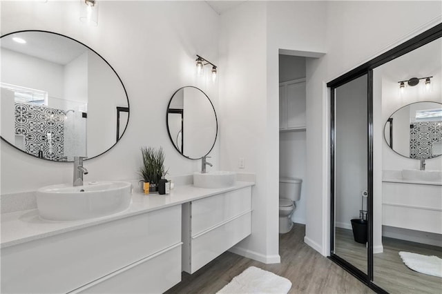 bathroom with hardwood / wood-style floors, vanity, toilet, and a shower