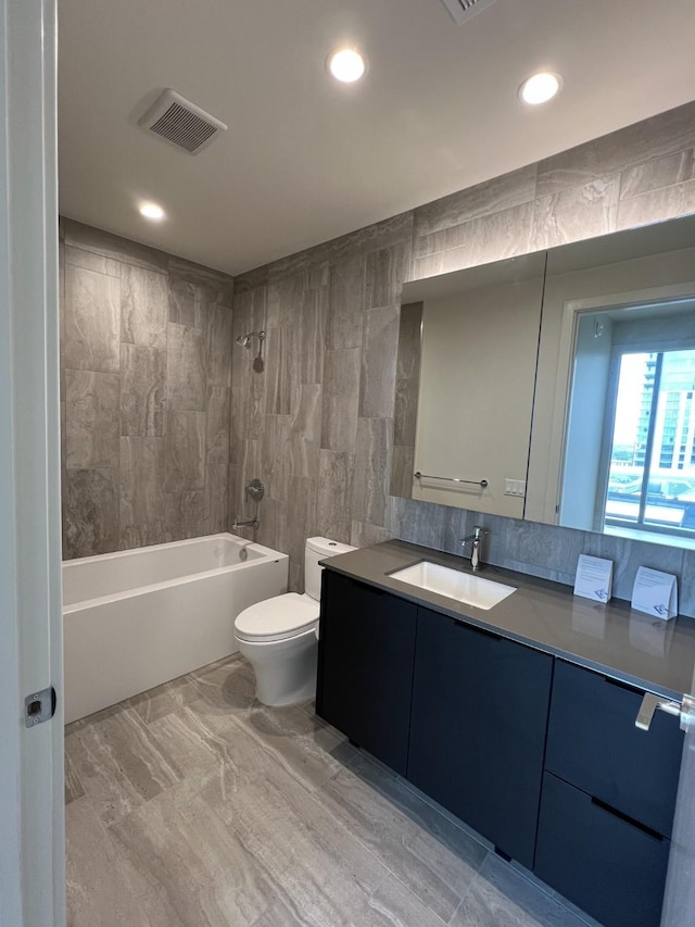 full bathroom with shower / tub combination, vanity, toilet, and tile walls