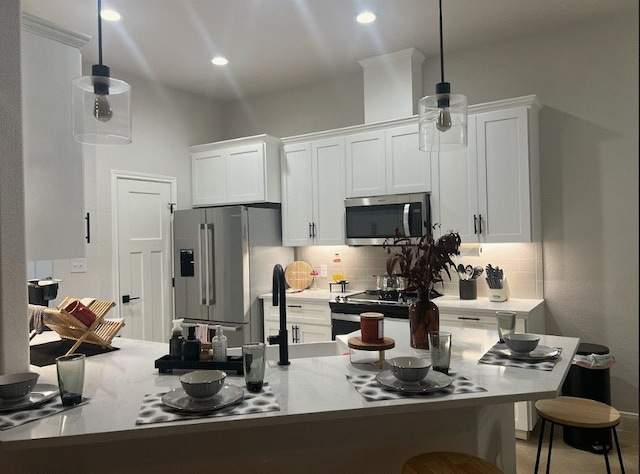 kitchen with pendant lighting, tasteful backsplash, white cabinetry, a kitchen bar, and stainless steel appliances