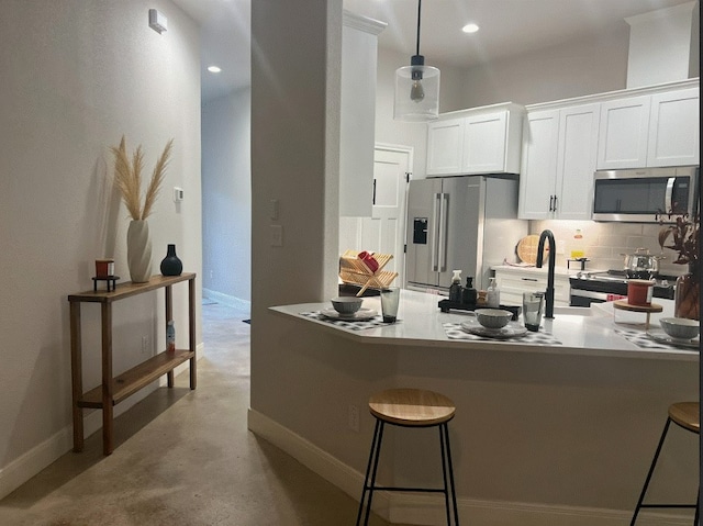 kitchen with appliances with stainless steel finishes, a breakfast bar, tasteful backsplash, and white cabinetry