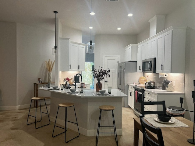 kitchen with a breakfast bar, sink, white cabinets, hanging light fixtures, and appliances with stainless steel finishes