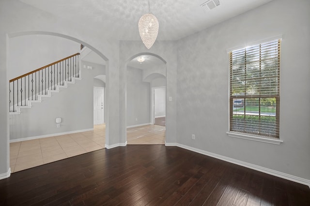 spare room with a notable chandelier and light hardwood / wood-style floors