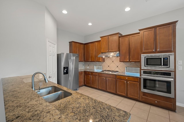 kitchen with decorative backsplash, light stone countertops, light tile patterned floors, stainless steel appliances, and sink