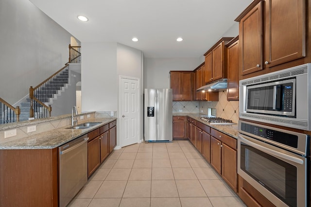 kitchen featuring tasteful backsplash, light tile patterned flooring, sink, appliances with stainless steel finishes, and light stone countertops