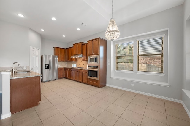 kitchen with sink, decorative backsplash, stainless steel appliances, decorative light fixtures, and light stone countertops