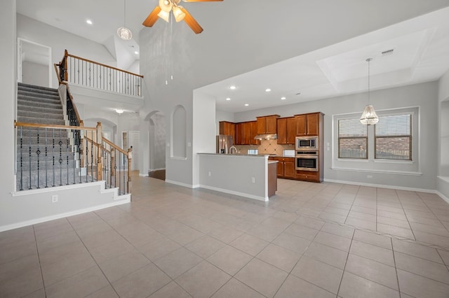 unfurnished living room with light tile patterned floors, a high ceiling, and ceiling fan