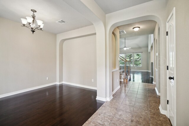 corridor with dark wood-type flooring and an inviting chandelier