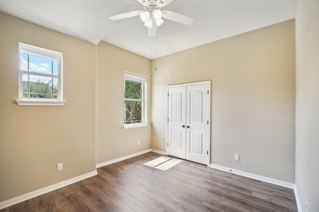 empty room featuring wood-type flooring, ceiling fan, and a healthy amount of sunlight