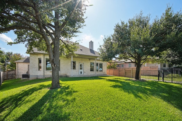 rear view of property with central AC and a lawn