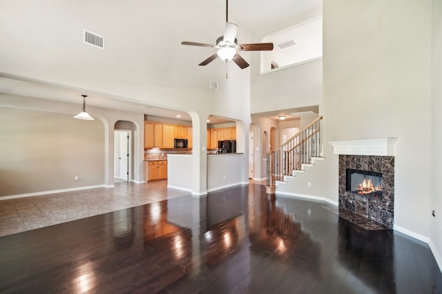 living room with dark wood-type flooring, a high end fireplace, high vaulted ceiling, and ceiling fan