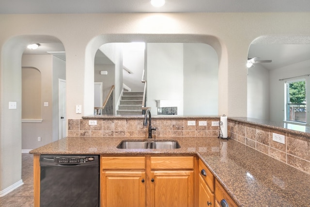 kitchen with ceiling fan, tasteful backsplash, sink, dark stone counters, and dishwasher