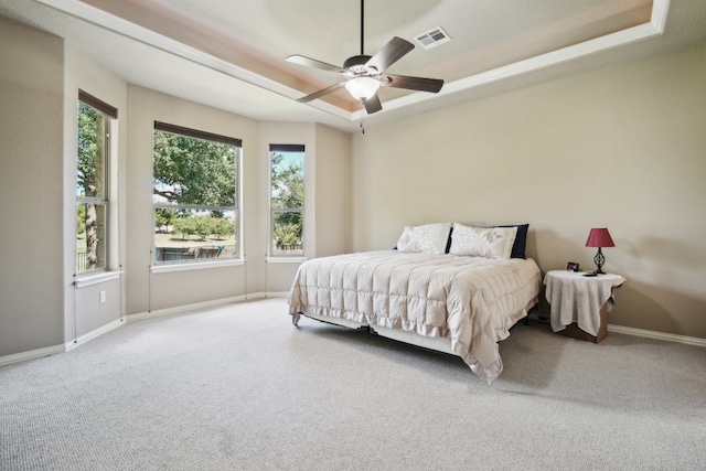 carpeted bedroom featuring a tray ceiling and ceiling fan