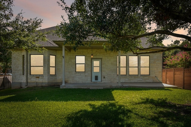 back house at dusk with a yard and a patio area