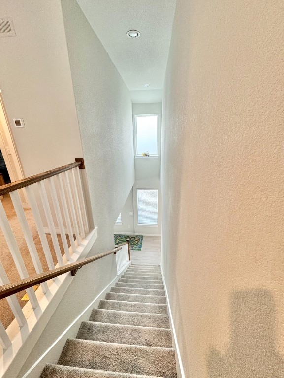 staircase with a textured ceiling and carpet