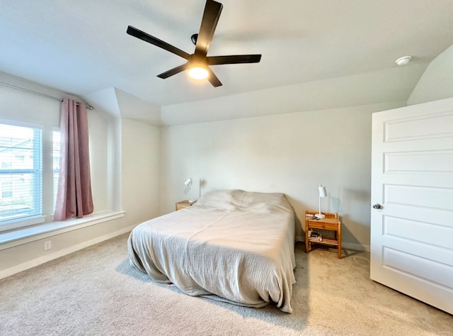 bedroom with ceiling fan, light colored carpet, and vaulted ceiling