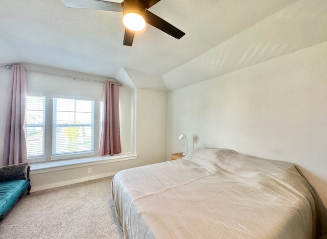 carpeted bedroom with a textured ceiling, vaulted ceiling, and ceiling fan