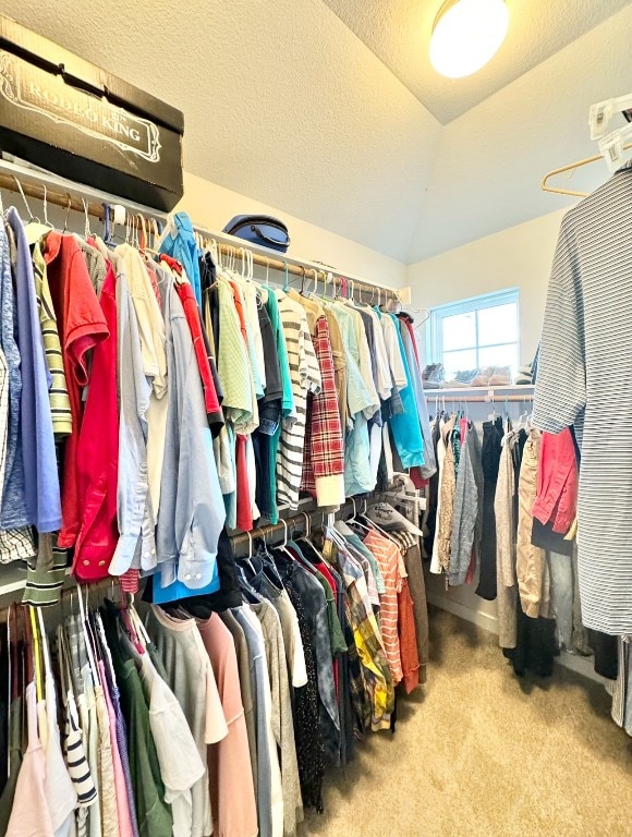 spacious closet with vaulted ceiling and light carpet