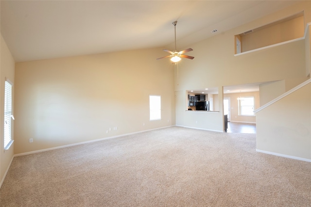 unfurnished living room featuring high vaulted ceiling, ceiling fan with notable chandelier, and carpet