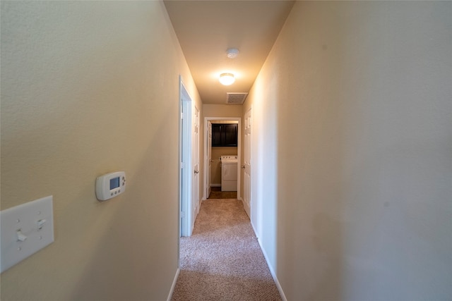 corridor with light carpet and washer / dryer