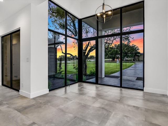 doorway to outside with concrete flooring, a wall of windows, and a chandelier