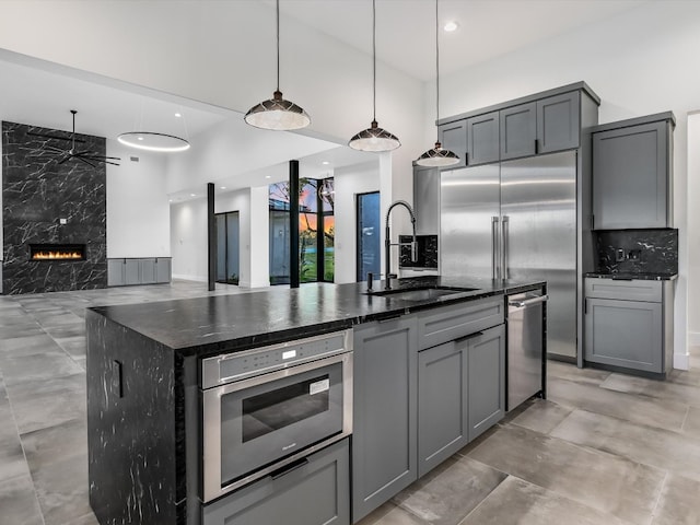 kitchen featuring an island with sink, pendant lighting, gray cabinets, and stainless steel appliances