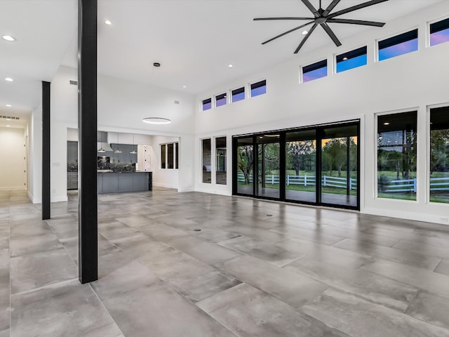 unfurnished living room featuring a towering ceiling and ceiling fan