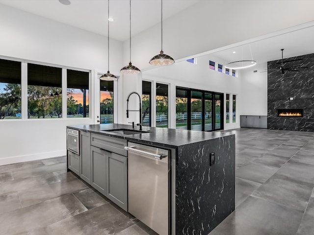 kitchen featuring an island with sink, decorative light fixtures, sink, and a wealth of natural light