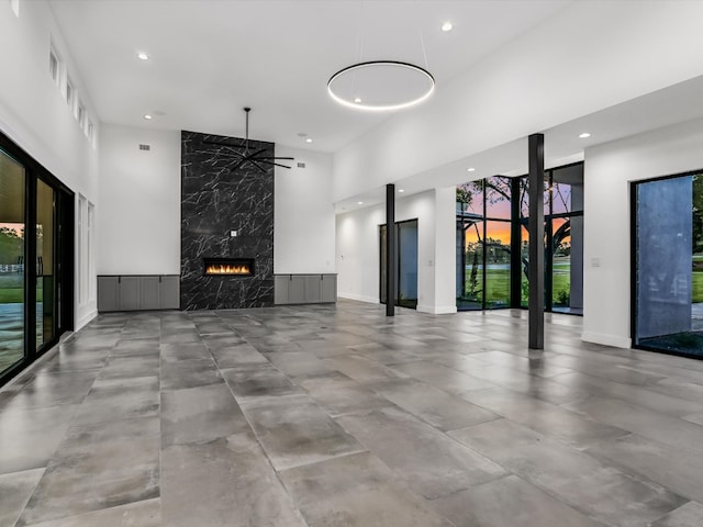 unfurnished living room with a towering ceiling, a fireplace, and tile walls