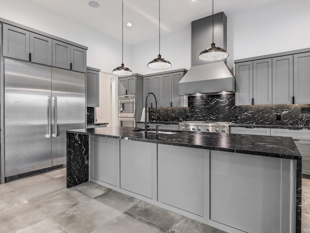 kitchen featuring a kitchen island with sink, decorative light fixtures, sink, backsplash, and appliances with stainless steel finishes