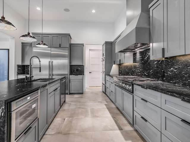 kitchen featuring tasteful backsplash, dark stone countertops, premium range hood, pendant lighting, and gray cabinets