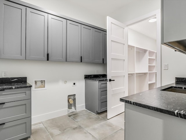 clothes washing area with sink, electric dryer hookup, light tile patterned flooring, washer hookup, and cabinets