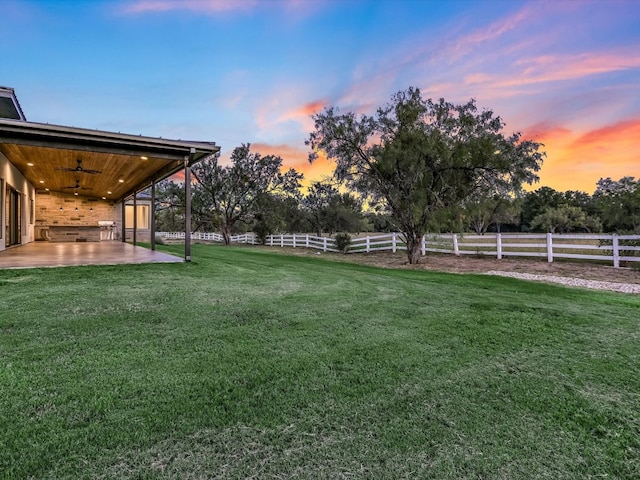 yard at dusk with a patio and ceiling fan