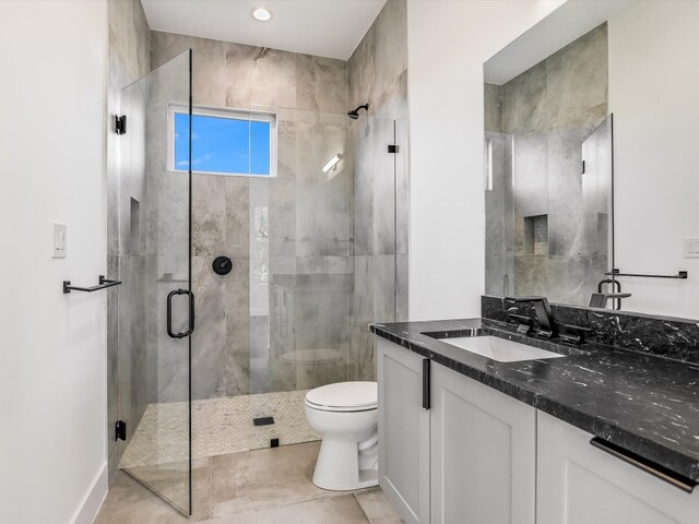 bathroom featuring vanity, toilet, a shower with door, and tile patterned floors