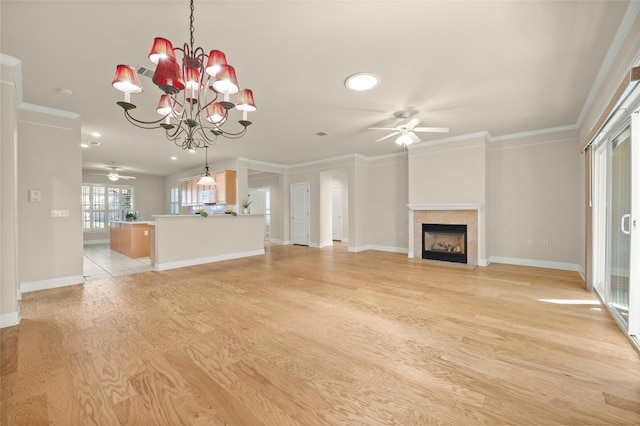 unfurnished living room featuring a tile fireplace, crown molding, light hardwood / wood-style floors, and ceiling fan with notable chandelier