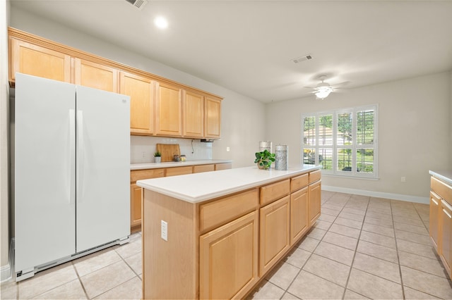 kitchen featuring light brown cabinetry, tasteful backsplash, white fridge, a kitchen island, and light tile patterned flooring