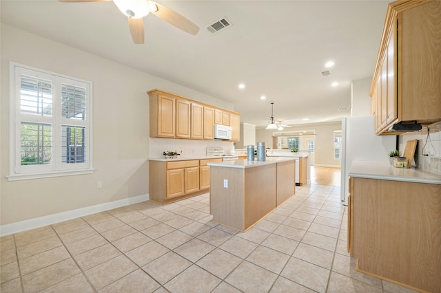 kitchen with white appliances, light brown cabinets, light tile patterned floors, a kitchen island, and hanging light fixtures